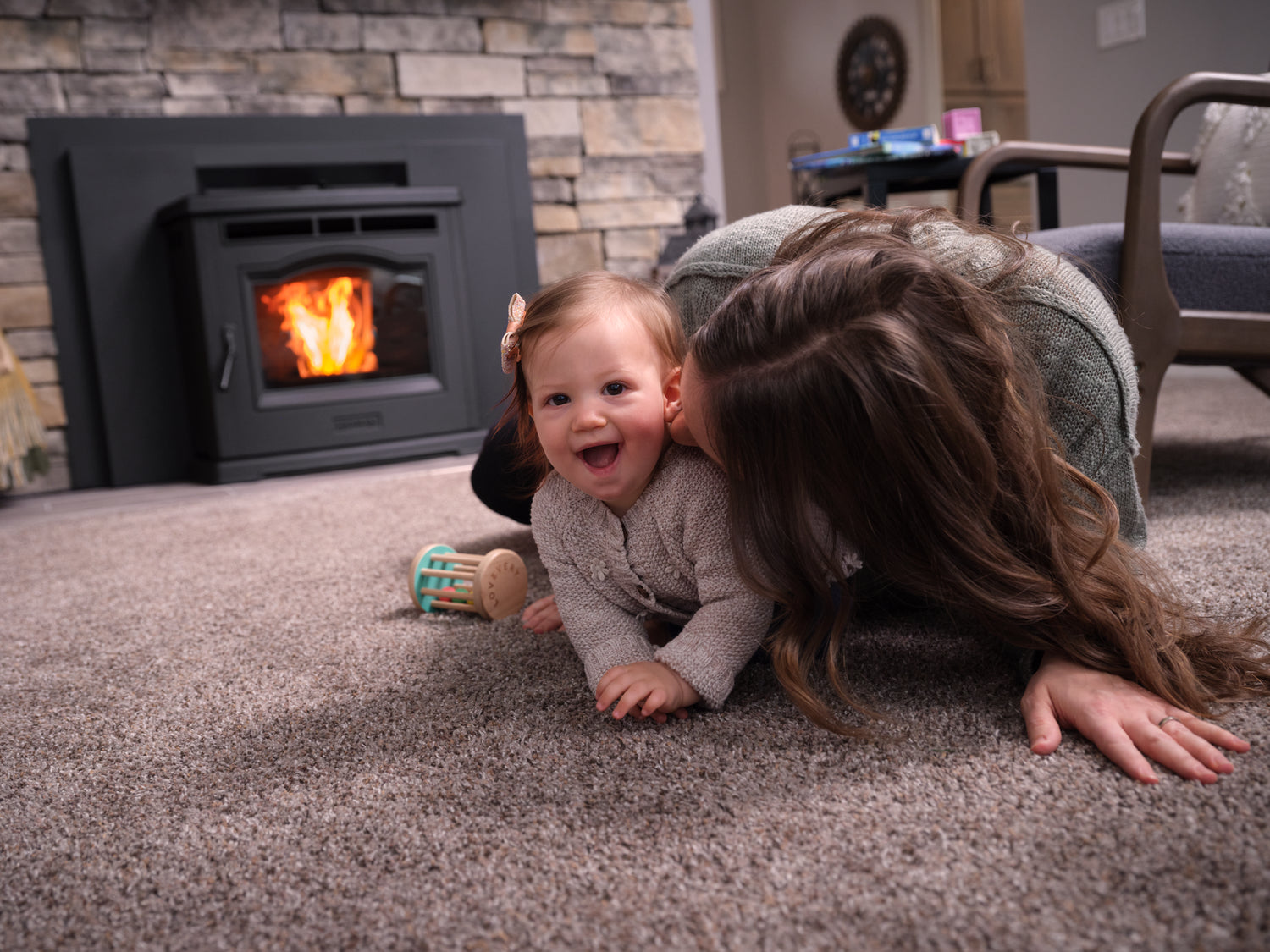 A mother playing with her baby on the floor in front of a fireplace
