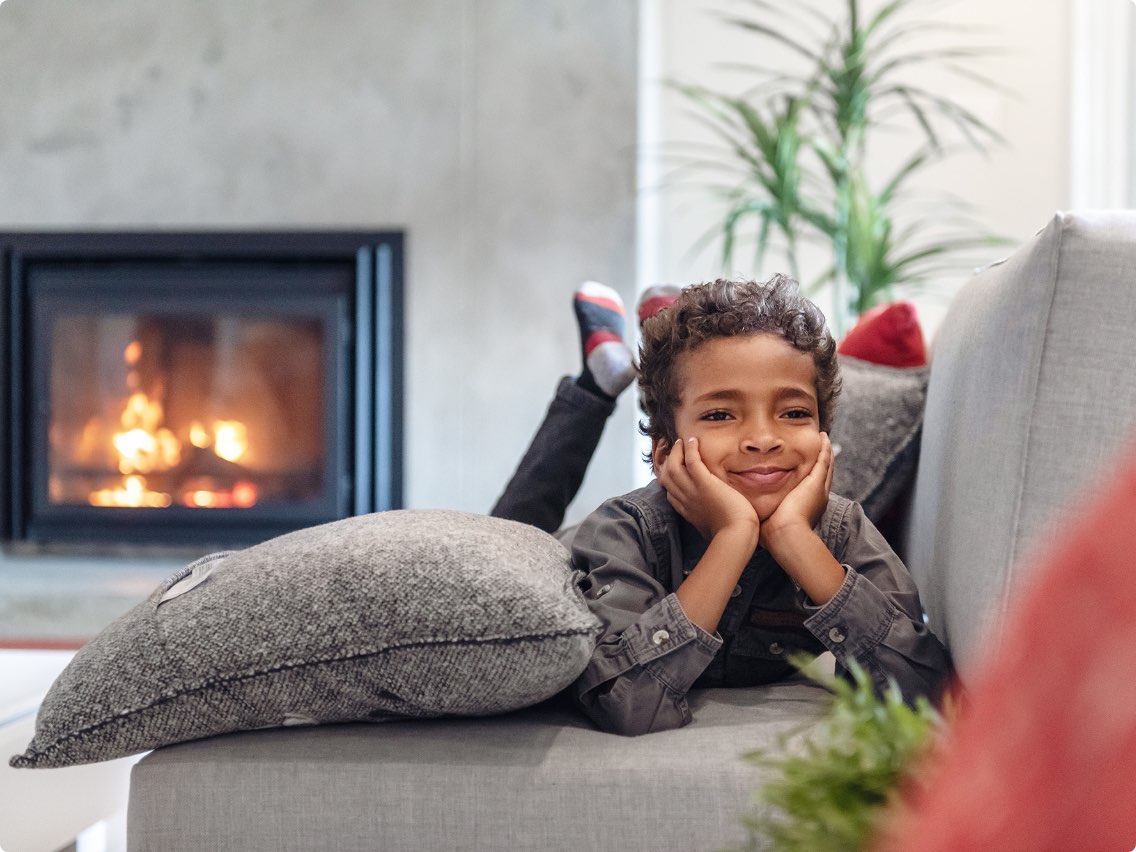 Kid laying on a couch with a fireplace in the background