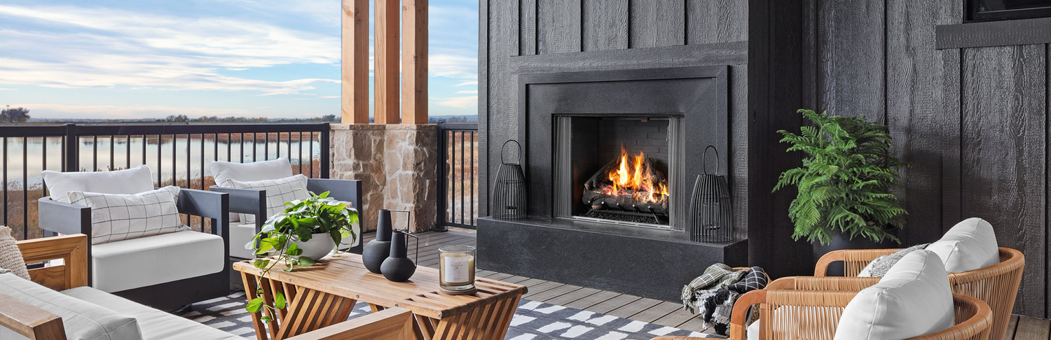 Outdoor patio with a lit fireplace overlooking water