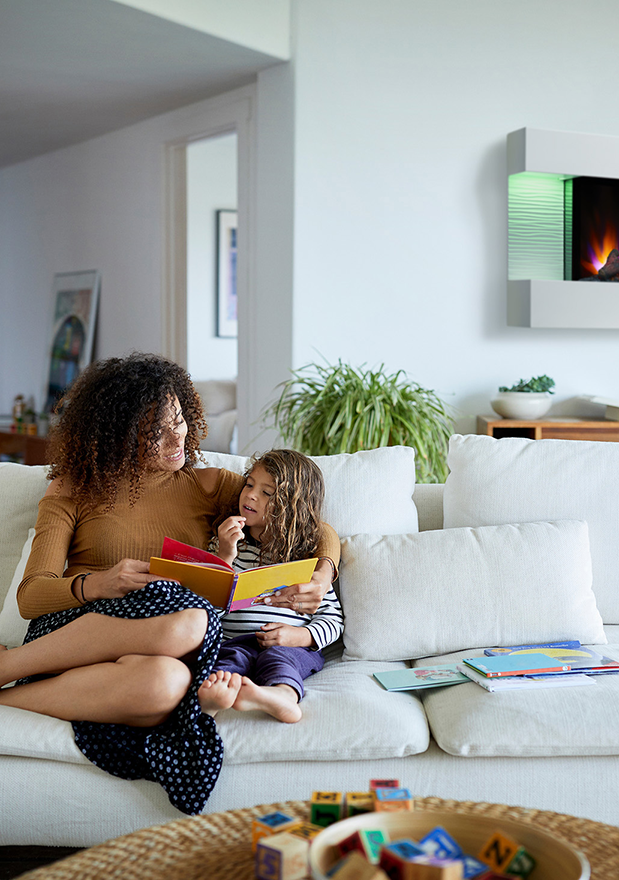 Mother reading to her daughter on the couch