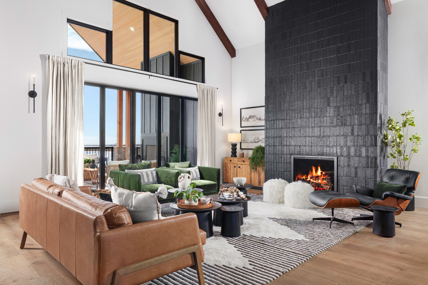Living room of a home with a tall black tile fireplace as its centerpiece